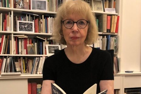 Portrait of Marielouise Jurreit with an open book in her hand.