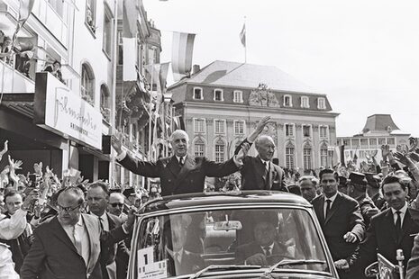 Fransa Cumhurbaşkanı Charles de Gaulle ve Almanya Şansölyesi Konrad Adenauer 1962 yılında üstü açık bir arabayla Bonn pazarından geçerken el sallıyorlar