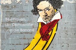 Eine Banane mit Beethoven-Gesicht vor einer abgerockten Wand